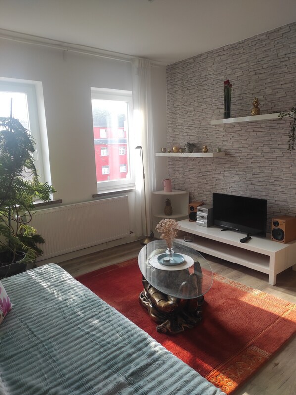 A modern living room with a fireplace, a television, and a large window.