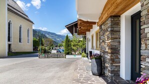 Un bâtiment doté d’une façade en pierre, d’un avant-toit en bois et offrant une vue dégagée sur les montagnes en arrière-plan.