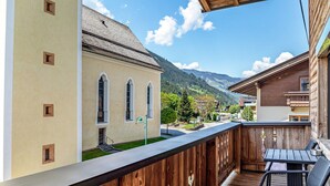 Un balcon en bois offrant une vue sur une montagne et un bâtiment doté de fenêtres en arc de cercle.
