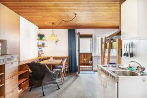 Eine kleine Küche mit Holzausstattung, ein Essbereich mit einer Bank und ein Blick nach draußen.