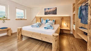 A bedroom with a wooden bed, bedside tables, a wardrobe, and a window. - Holiday Home Wendelhof Apartment Fuchsbau (Eisenbach (Hochschwarzwald))