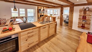 A modern kitchen with wooden cabinetry, a built-in oven, and a large island with a sink. - Holiday Home Wendelhof Apartment Fuchsbau (Eisenbach (Hochschwarzwald))