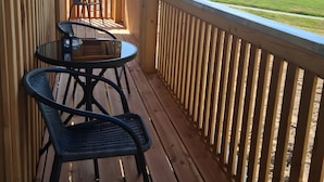 Une terrasse en bois avec une table et des chaises, donnant sur un paysage verdoyant.