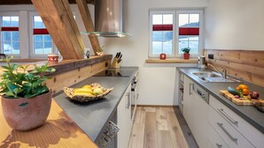 Une cuisine moderne avec des poutres en bois, un grand îlot central et une vue sur un paysage enneigé par les fenêtres.