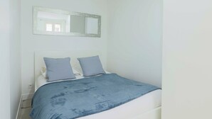 A bedroom with a bed, two pillows, a bedside table, and a mirror on the wall. - Flat 1BDR/2P Roland Garros/Parc des (Boulogne-Billancourt)