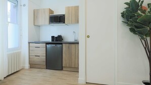 A compact kitchen with wooden cabinets, a built-in microwave, a coffee machine, and a dishwasher. - Flat 1BDR/2P Roland Garros/Parc des (Boulogne-Billancourt)