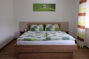 A bed with a green and white polka dot bedspread, wooden headboard, bedside tables with lamps, and a painting on the wall. - Apartment 'Belchen, Type B' with Mountain View, Balcony and Wi-Fi in Münstertal (Münstertal)