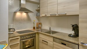 A modern kitchen with a built-in oven, a coffee maker, and a sink.