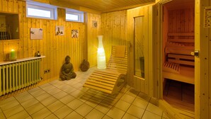 A sauna room with wooden walls, a statue, a massage table, and a bottle of water.
