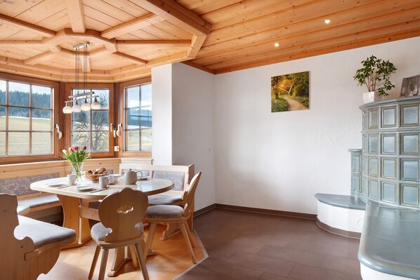 Un coin repas en bois avec une table ronde, des chaises et un banc.