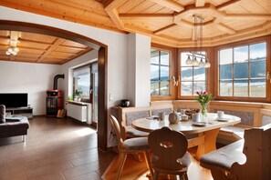 Un vaste espace de vie doté d’une grande fenêtre, d’un plafond en bois et d’une table à manger avec des chaises.
