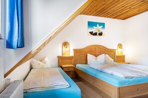 A bedroom with two beds, wooden headboards, bedside lamps, a radiator, and a ceiling with wooden beams. - Holiday Apartment 'Schöne Aussicht, 60sqm' with Shared Garden, Balcony and Wi-Fi (Titisee-Neustadt)