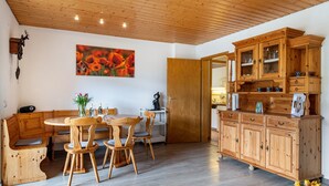 A wooden dining table with chairs, a wooden bench, a cabinet with glass doors, and a painting on the wall. - Holiday Apartment 'Schöne Aussicht, 60sqm' with Shared Garden, Balcony and Wi-Fi (Titisee-Neustadt)