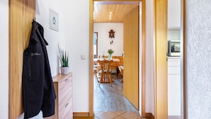 A hallway leading to a dining area with wooden furniture and a clock on the wall. - Holiday Apartment 'Schöne Aussicht, 60sqm' with Shared Garden, Balcony and Wi-Fi (Titisee-Neustadt)