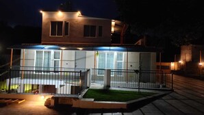 Ein modernes, zweistöckiges Haus mit überdachter Terrasse und kleinem Rasen.