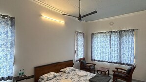 Ein Schlafzimmer mit einem Bett, zwei Stühlen, einem kleinen Tisch und einem Deckenventilator.
