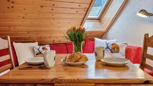 Une table de salle à manger en bois, avec une assiette de croissants, un vase de fleurs et une tasse.