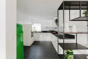 Una cocina moderna con armarios blancos, encimera negra y refrigerador verde.