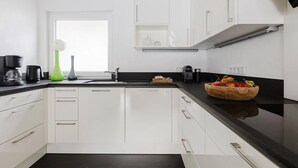 A modern kitchen with white cabinets, a black countertop, and a fruit bowl. - Apartment 'Waldzauber' with Balcony and Wi-Fi (Lennestadt)