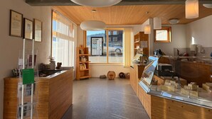 Un interior moderno con detalles de madera, una recepción, una vitrina con queso y vistas al exterior.
