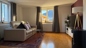 Una sala de estar con un sofá, una mesita, un televisor y una lámpara.
