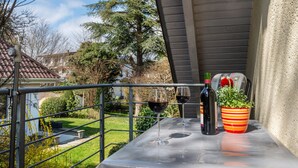 Ein Balkon mit Tisch, zwei Weingläsern und einem Blumentopf.