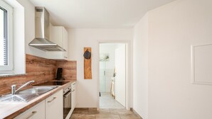 A modern kitchen with a wooden countertop, stainless steel sink, and a range hood. - Bergliebe Apartment with Private Terrace and Wi-Fi (Sasbach)
