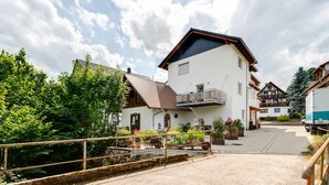A traditional chalet with a balcony, surrounded by lush greenery and a gravel driveway. - Bergliebe Apartment with Private Terrace and Wi-Fi (Sasbach)