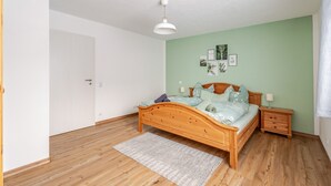 Un dormitorio con cama de madera, mesita de noche, lámpara de pared y una puerta.