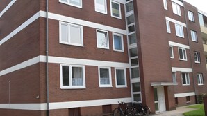 Een meerlaags bakstenen gebouw met ramen met witte kozijnen, een centrale trap en fietsen die er buiten staan.