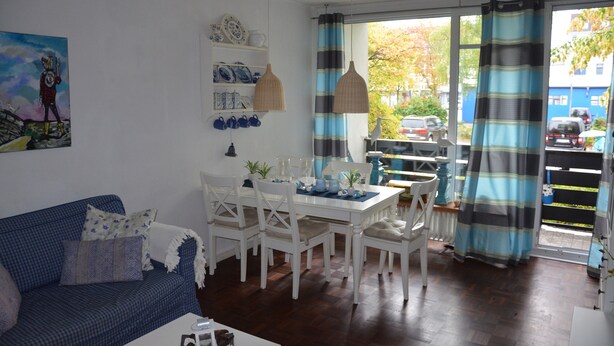 Een woonkamer met een bank, eettafel, stoelen en een schilderij aan de muur.