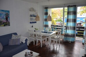 A living room with a sofa, dining table, chairs, and a painting on the wall.