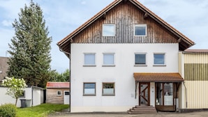 Un edificio a due piani con facciata bianca, diverse finestre e tetto in legno.
