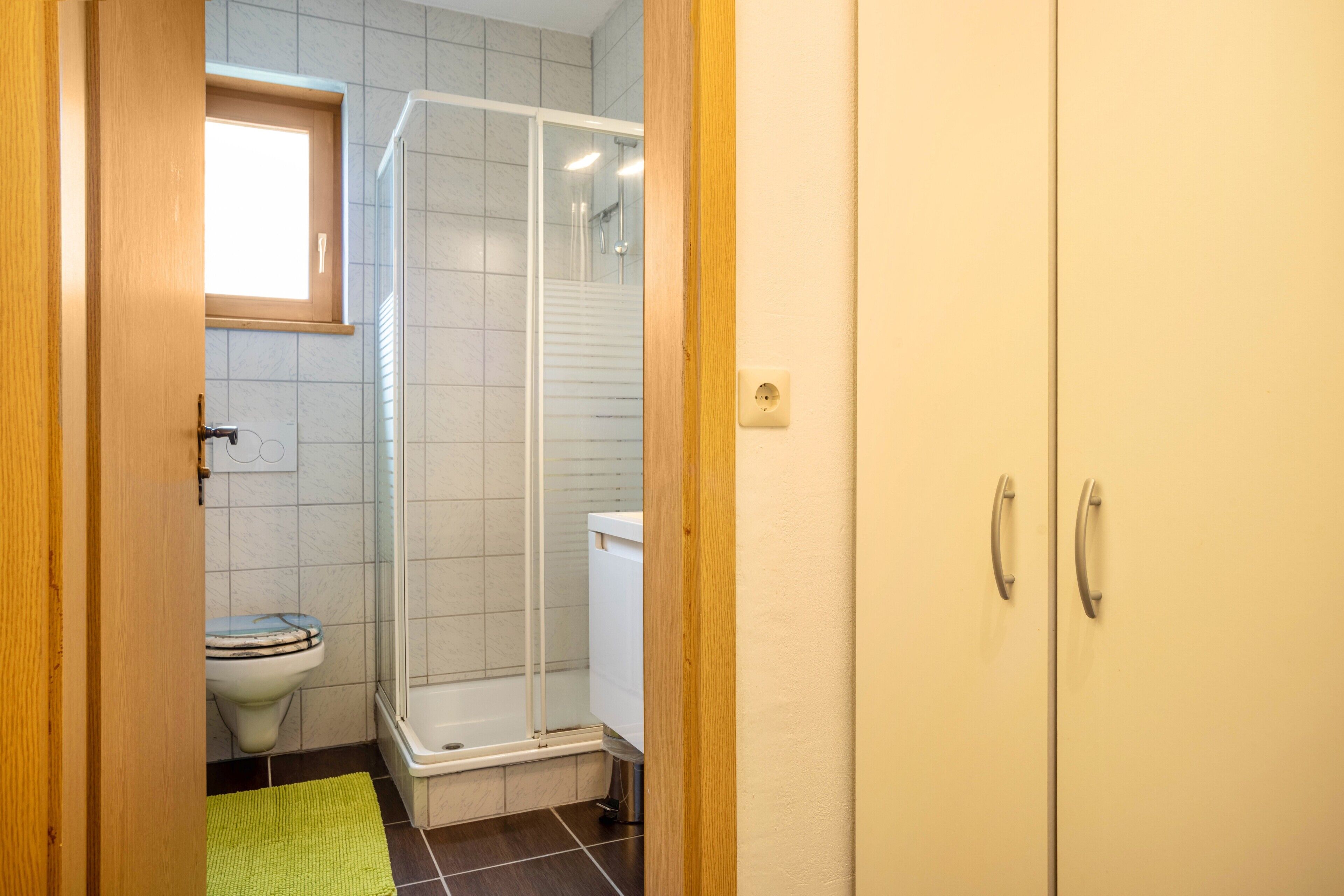 Et badeværelse med toilet, bruser og skab.