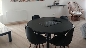 Una sala moderna con una mesa redonda negra, sillas negras, una obra de arte con un mapa del mundo, un televisor y una silla de mimbre.