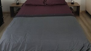 Un dormitorio con una cama, dos mesitas de noche y una lámpara en el techo.