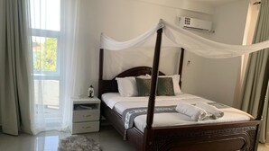 Ein Bett mit Baldachin, ein Nachttisch, eine Lampe und ein flauschiger Teppich.