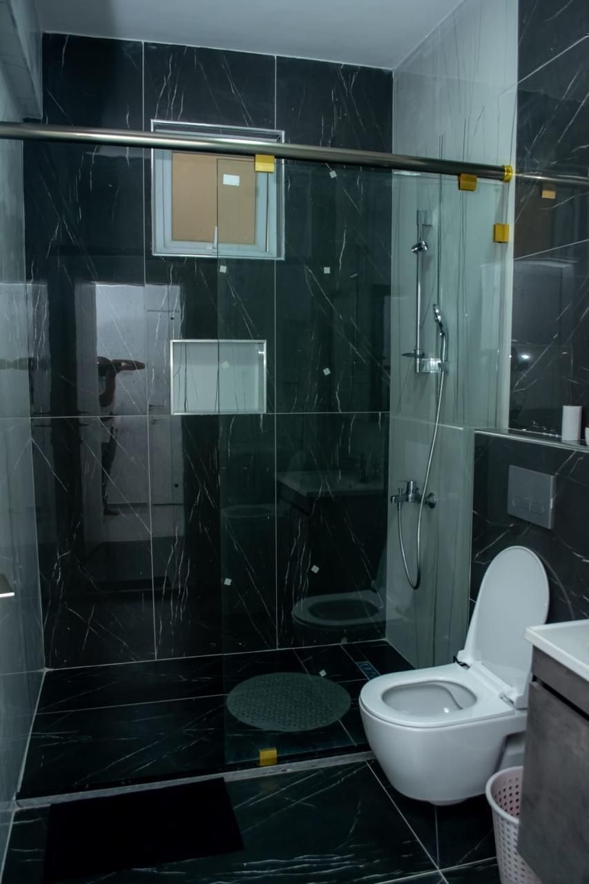 Un baño moderno con ducha de vidrio, inodoro y lavamanos.
