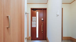 A hallway with a wooden door, a sign with text, and a tiled floor.