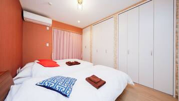 A hotel room with a bed, a wardrobe, and an air conditioning unit.
