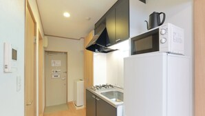 A compact kitchen with a refrigerator, stove, microwave, and a small sink.