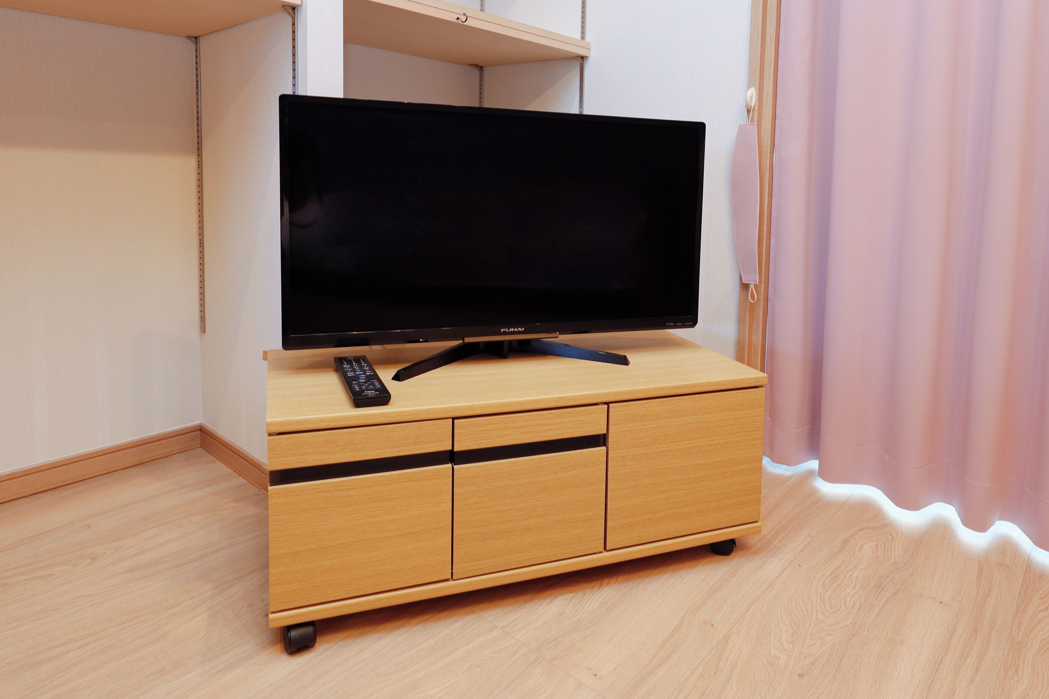 Un mueble bajo de madera para televisor con un televisor de pantalla plana y un control remoto.