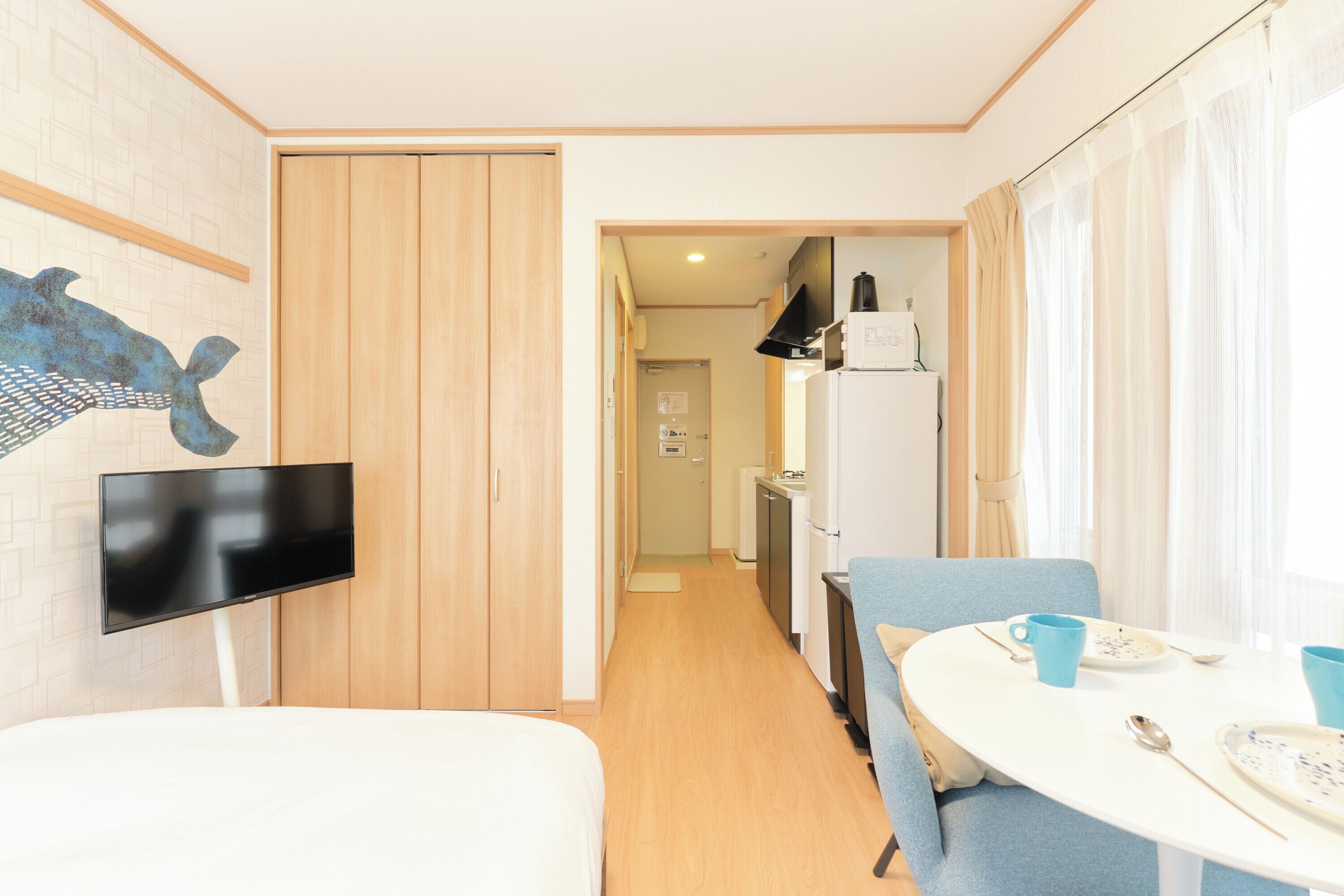Ein gemütlicher Raum mit Bett, Wand-Fernseher, Esstisch mit Stühlen und einer Küchenzeile im Hintergrund.