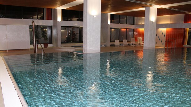 An indoor swimming pool with clear water, surrounded by white walls and wooden beams. - "Sunny spot" dreamy sunsets included! (Dahme)