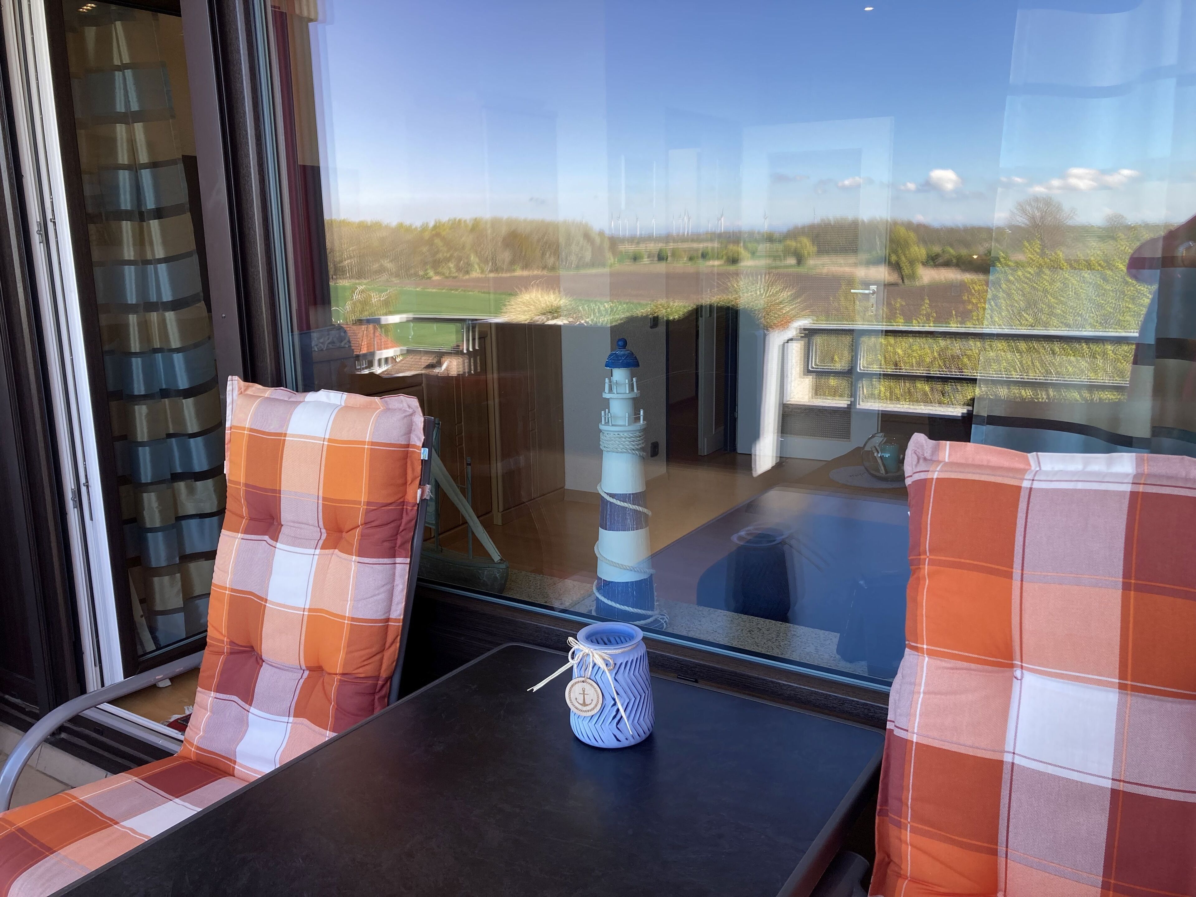 A balcony with two plaid chairs, a small table, and a decorative item.