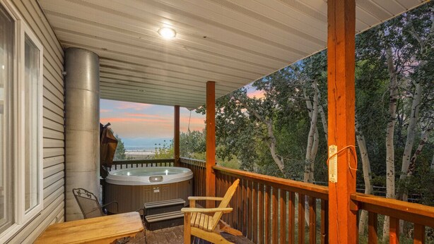 A wooden deck with a hot tub, a table, and two chairs. - Grand View Ranch | 500+ Acres, Hot Tub, Sleeps 25, Forest Access! (Tetonia)