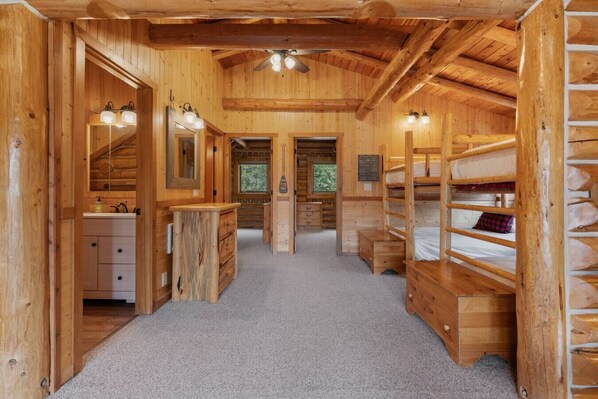 Innenansicht einer Holzhütte mit einem zentralen Gang, Holzwägelichen, einem Schminktisch mit Spiegel und einem kleinen Fenster.