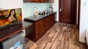 A kitchen with wooden cabinets, a refrigerator, a sink, and a stove. - Hanoi Apartment  (Hanoi)