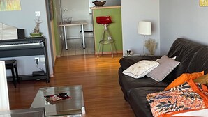 Ein Wohnzimmer mit einem Klavier, einer schwarzen Ledersofa und einem Glastisch.