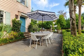 Un patio con una mesa redonda y sillas, una sombrilla y una puerta azul.